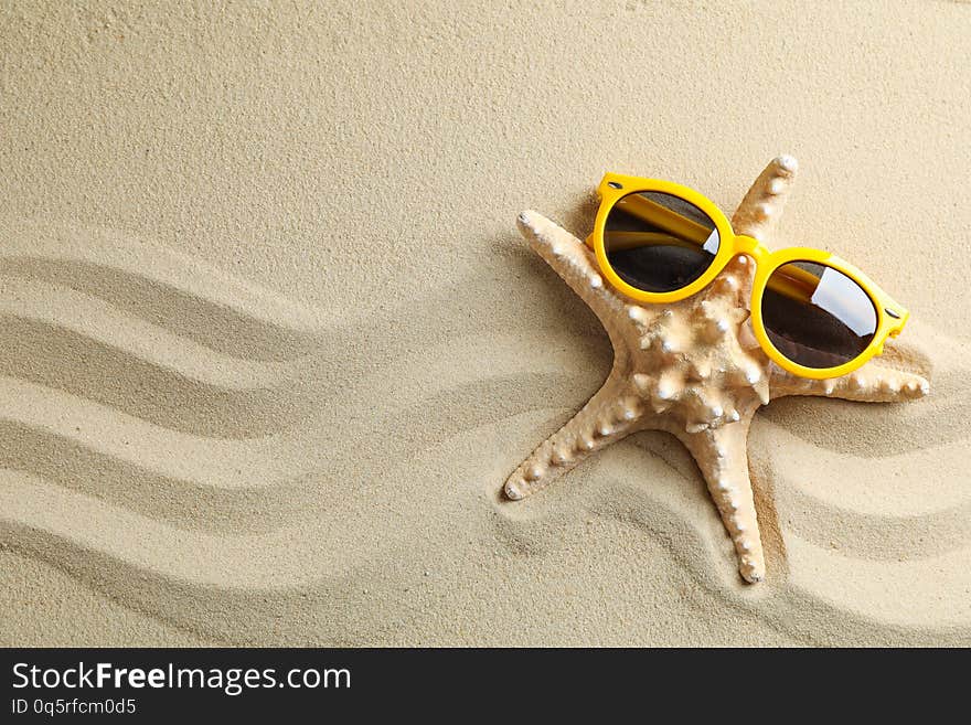 Clear sea sand with starfish and sunglasses, space for text. Summer vacation