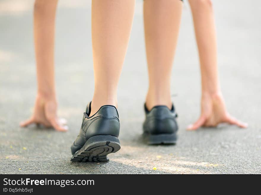 Female legs and hands put on the asphalt close-up, symbol of the start before the run, strong personality and marathon run. Horizontal frame