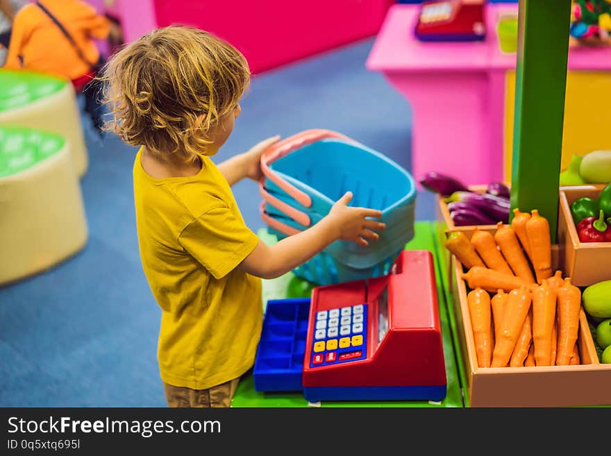 Boy shopping fruits and vegetables in a toy supermarket.