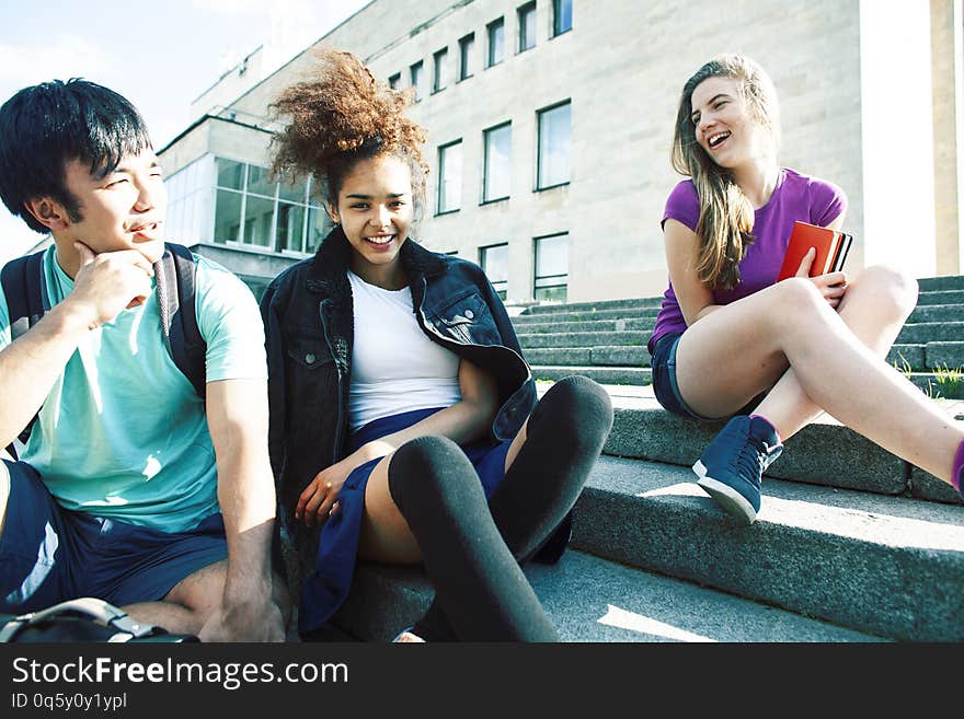 Cute group of teenages at the building of university with books huggings, diversity nations real students lifestyle