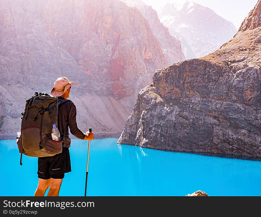 Man with backpack near lake Big Alo on rocky mountain background. Fann Mountains, Tajikistan, Central Asia