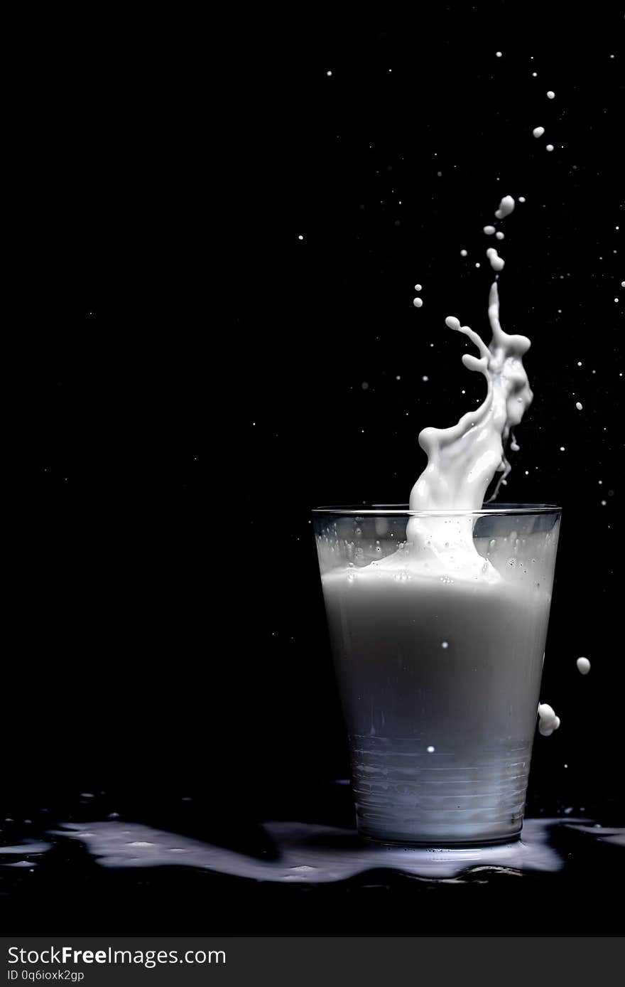 Milk glass splash isolated on black background. Closeup of splashing drops of white beverage or milkshake