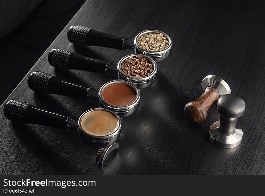 Four holders with green, roasted, ground, and hot coffee and tamper, equipment for making freshly brewed coffee