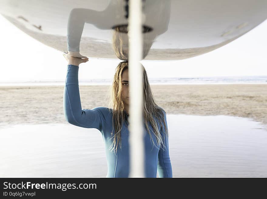 a surfer girl carrying a board on her head with the sea in the background on zarautz beach. a surfer girl carrying a board on her head with the sea in the background on zarautz beach