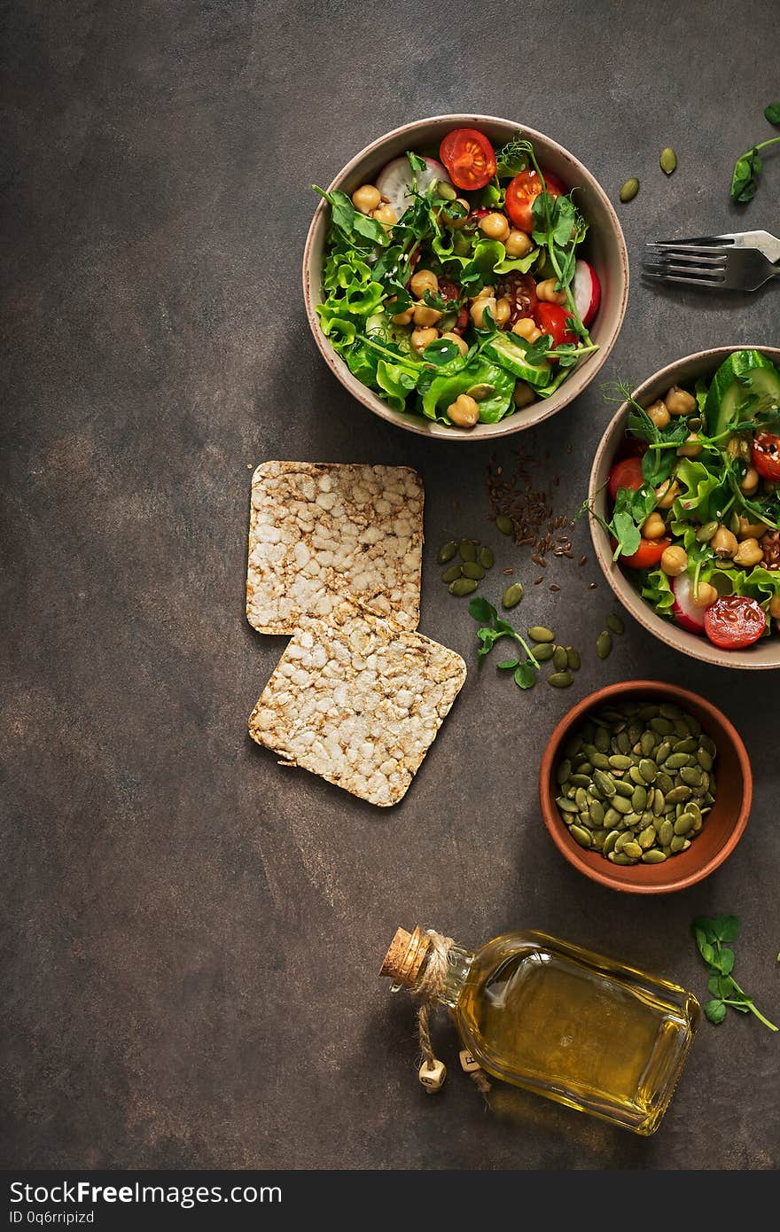 A bowl of vegan and vegetarian fresh vegetable salad and chickpeas on a dark background. Top view, copy space