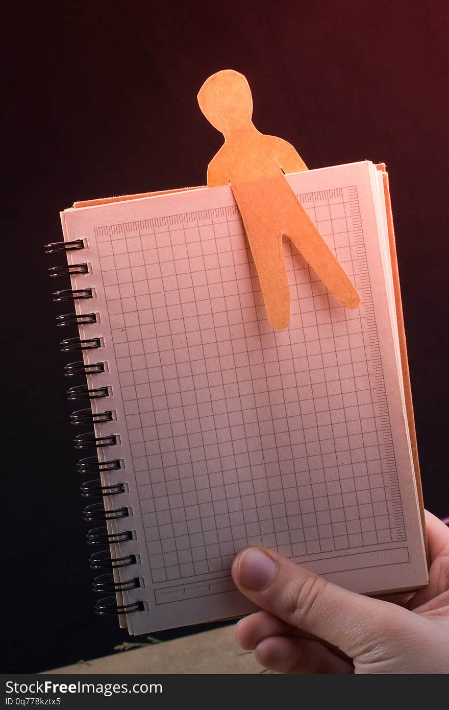 Man shape cut out of paper in notebbok in hand