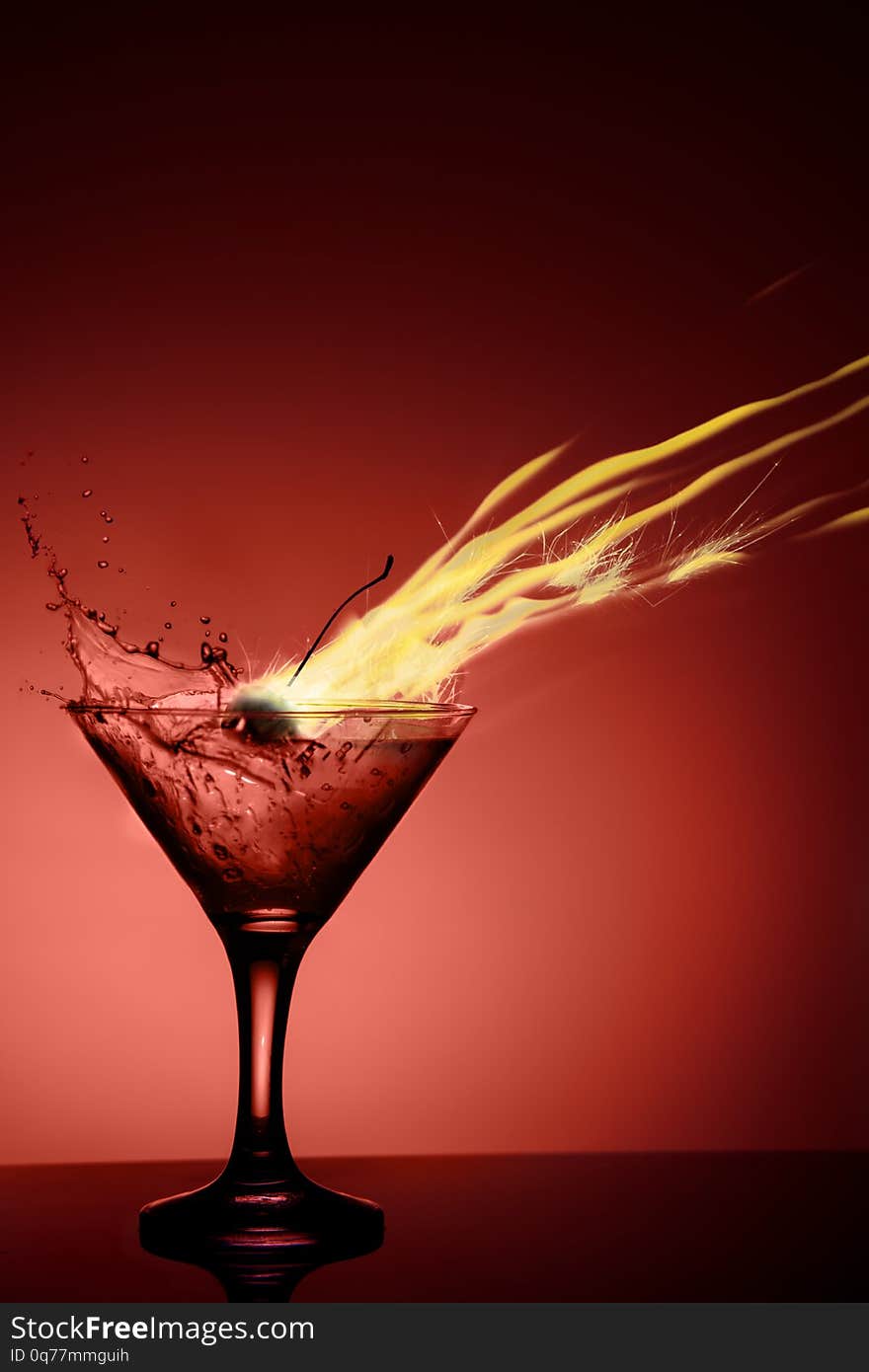 Alcoholic coctail with a flame and a splash on red background