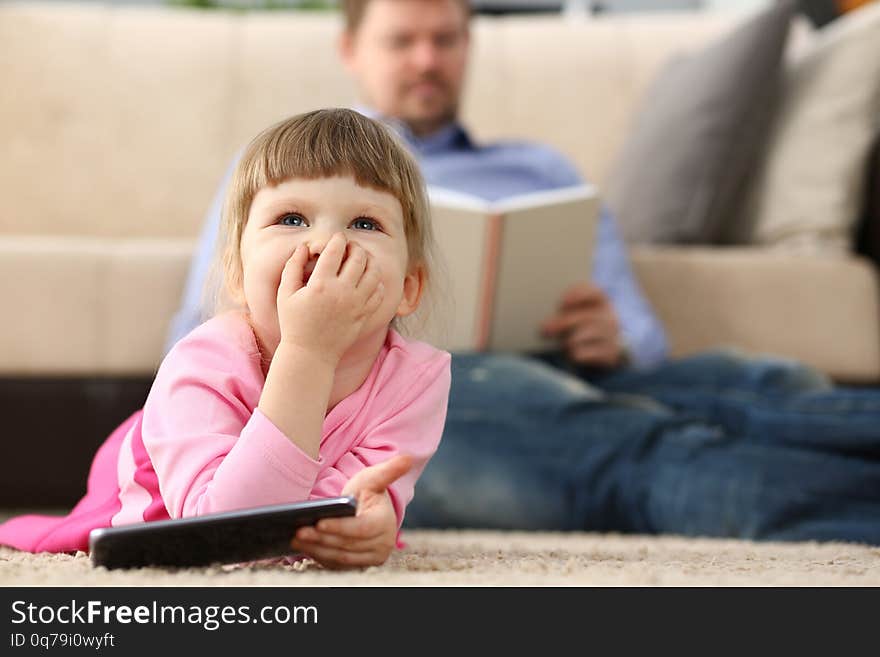 Father and daughter lie on floor using mobile phone portrait