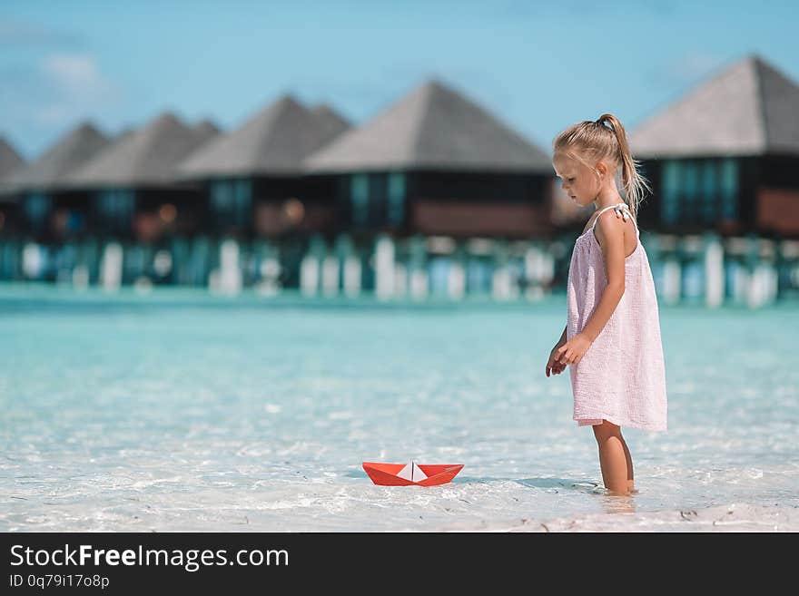 Cute child playing with paper boats in a sea