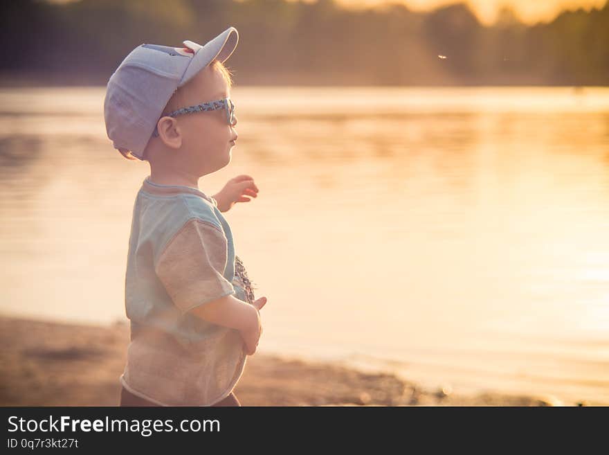 Child near water, orange sunset