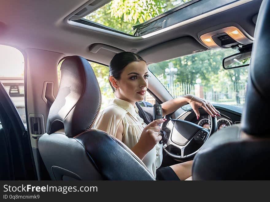 Smiling woman inside car with key from it