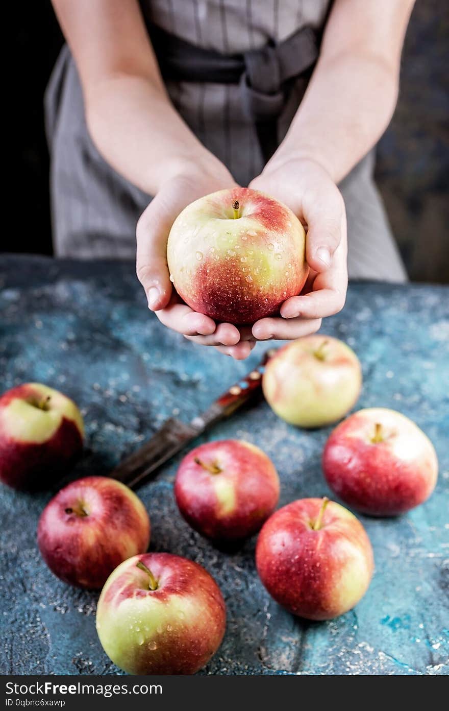 Girl hands hold an apple on a dark blue background. Autumn harvest