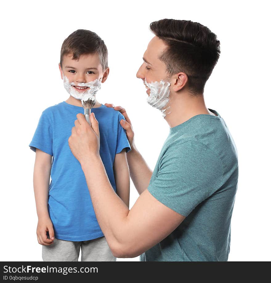 Dad applying shaving foam onto son`s face against white background