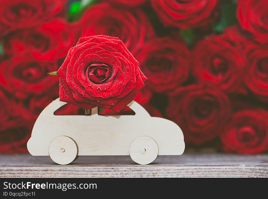 Concept of flower delivery, love, typewriter transports a flower against a background of red roses