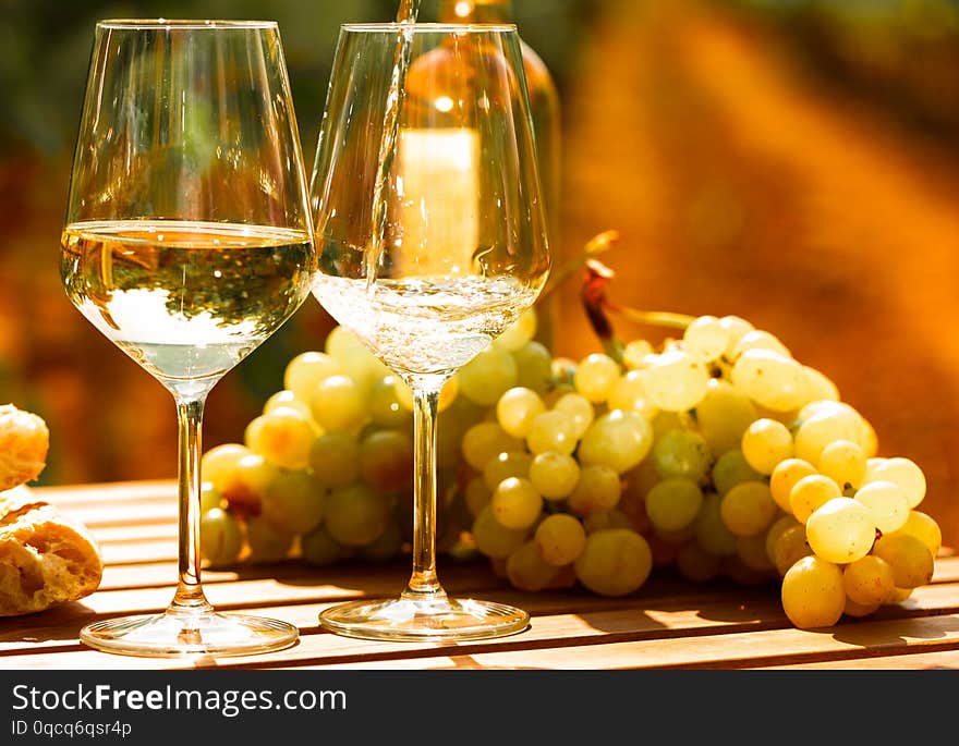 Glass of White wine ripe grapes and bread on table in vineyard