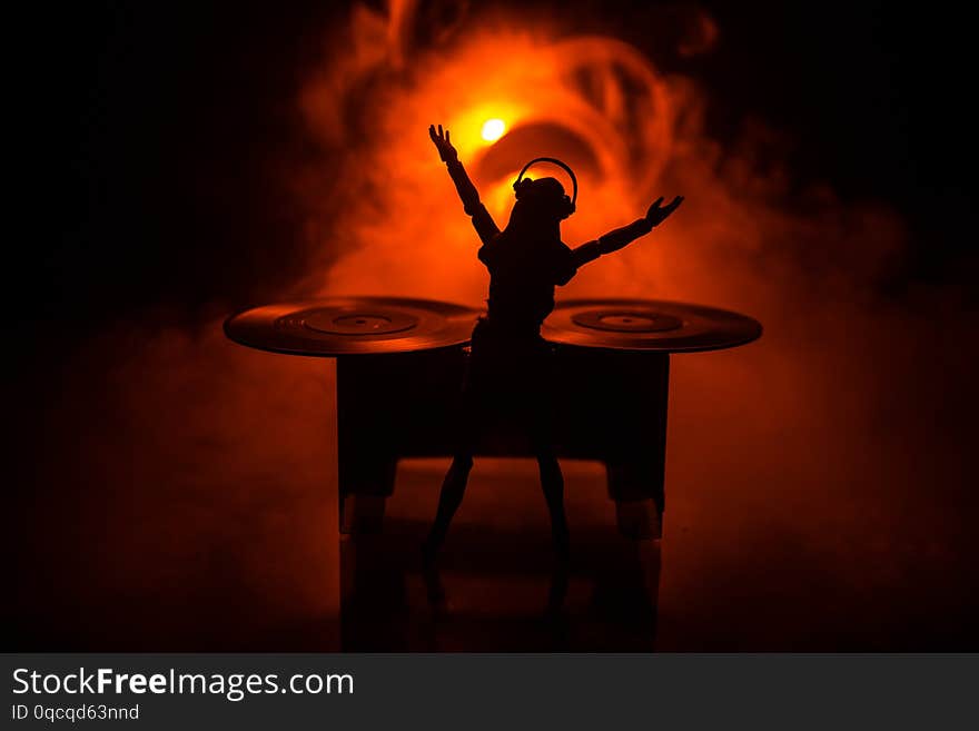 Dj club concept. Woman DJ mixing, and Scratching in a Night Club. Girl silhouette on dj s deck, strobe lights and fog on