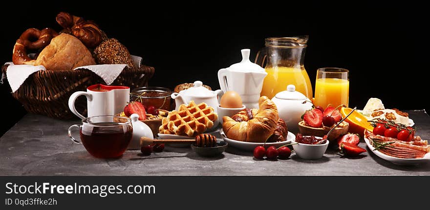 Huge healthy breakfast on table with coffee, orange juice, fruits, waffles and croissants. Good morning concept