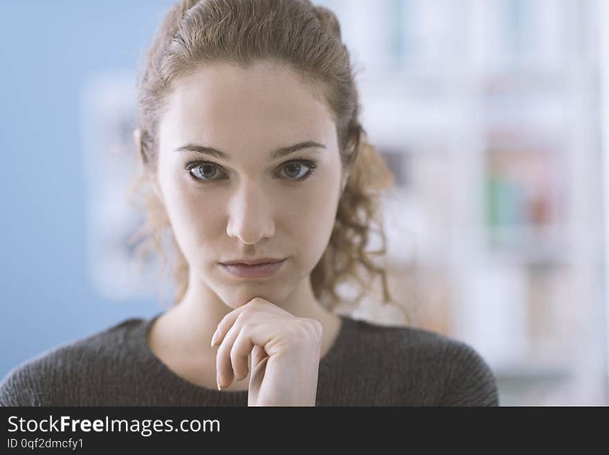 Young cute girl thinking with hand on chin and looking at camera
