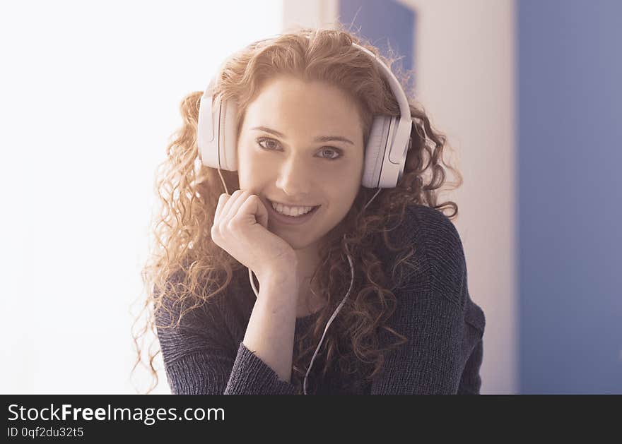 Smiling happy curly girl wearing headphones and posing, youth and fun concept. Smiling happy curly girl wearing headphones and posing, youth and fun concept