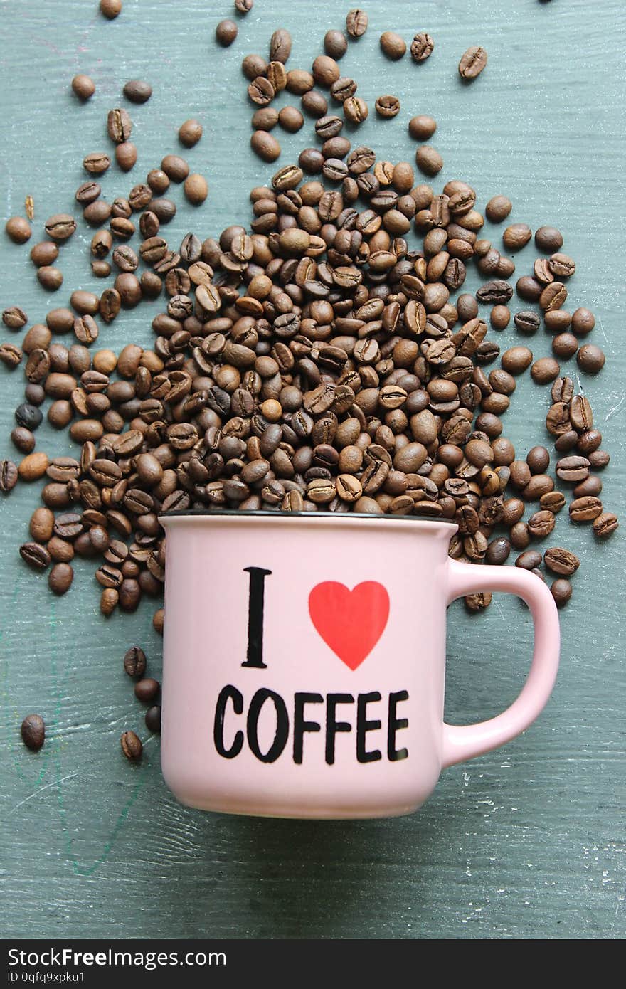 I love coffee. glass Cup close-up with the name I love coffee. Grey grunge background and lots of scattered coffee beans. Copy space