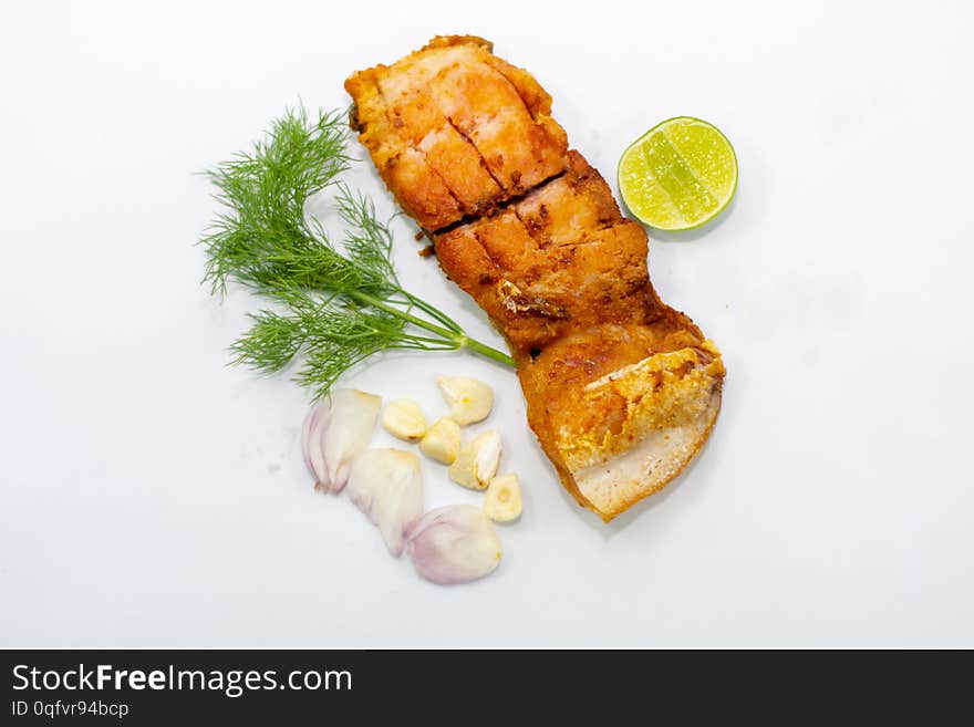 Fried marinated fish fillets with vegetables, onions, garlic on top