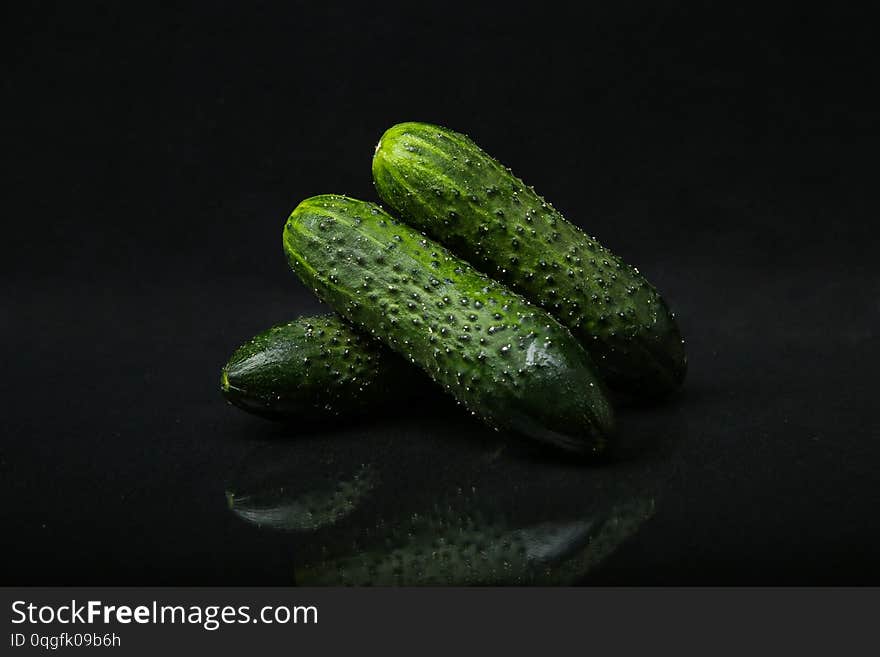 Cucumbers with pimples isolated on a black background with reflection