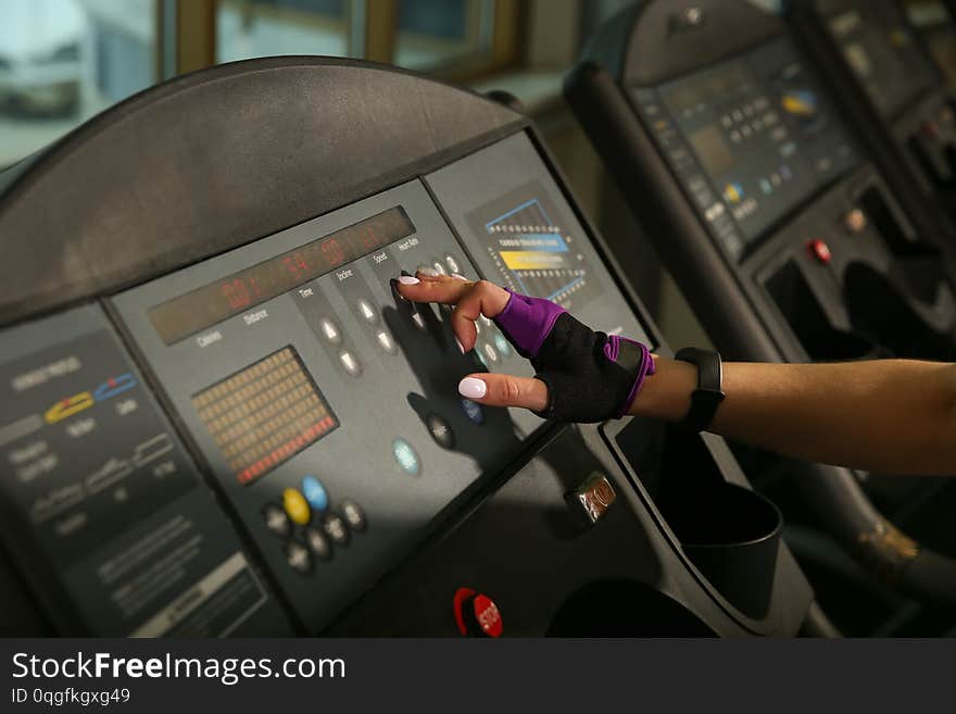 The female hand presses the button on the treadmill. the girl`s finger presses the button. the settings of the treadmill.