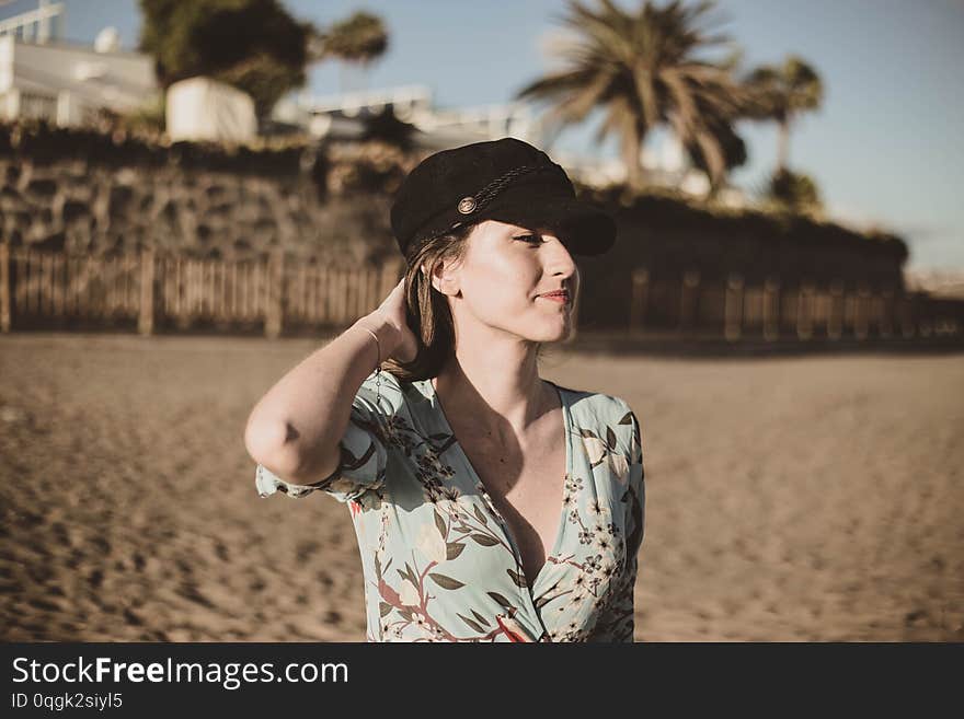 Beautiful young woman portrait in the desert touching her hair with a black cap