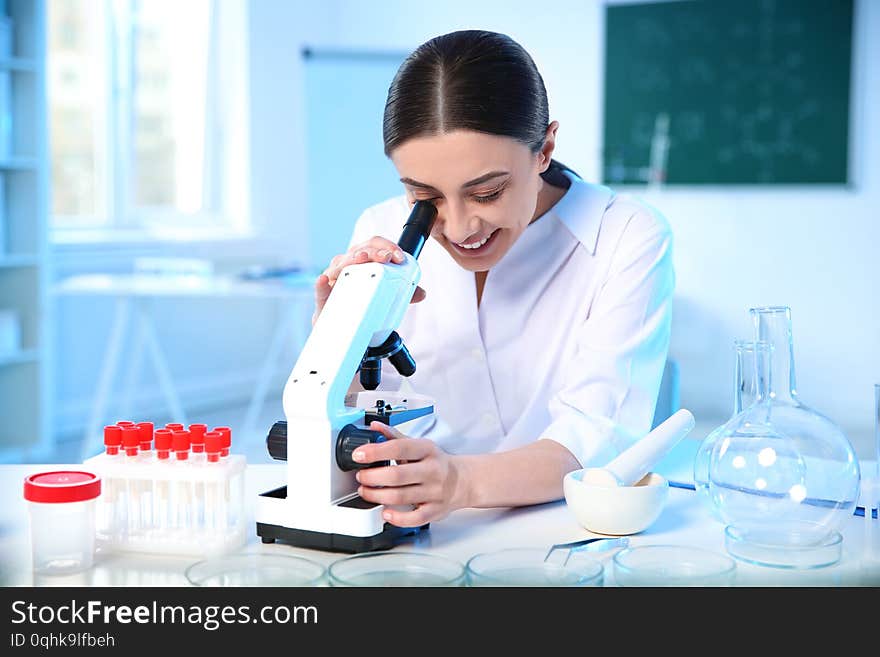 Female scientist using modern microscope in laboratory