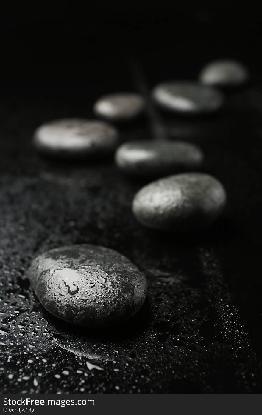 Wet spa stones on black background. Space for text