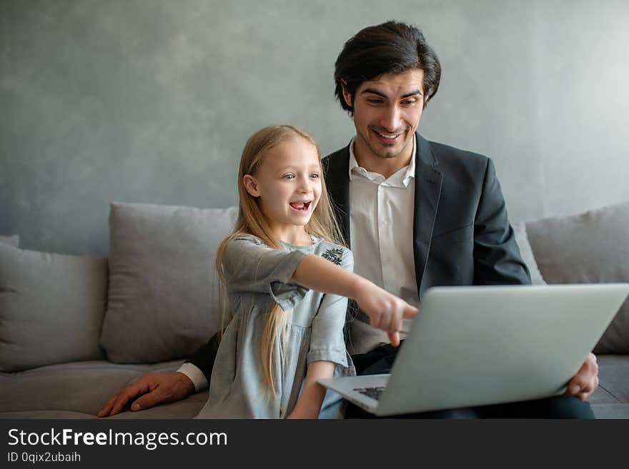 Happy little girl watching a movie on the computer with her father