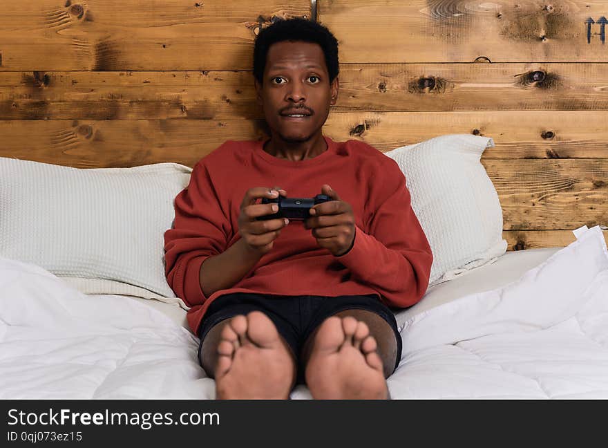 Young afro man having fun playing games in the bed at home