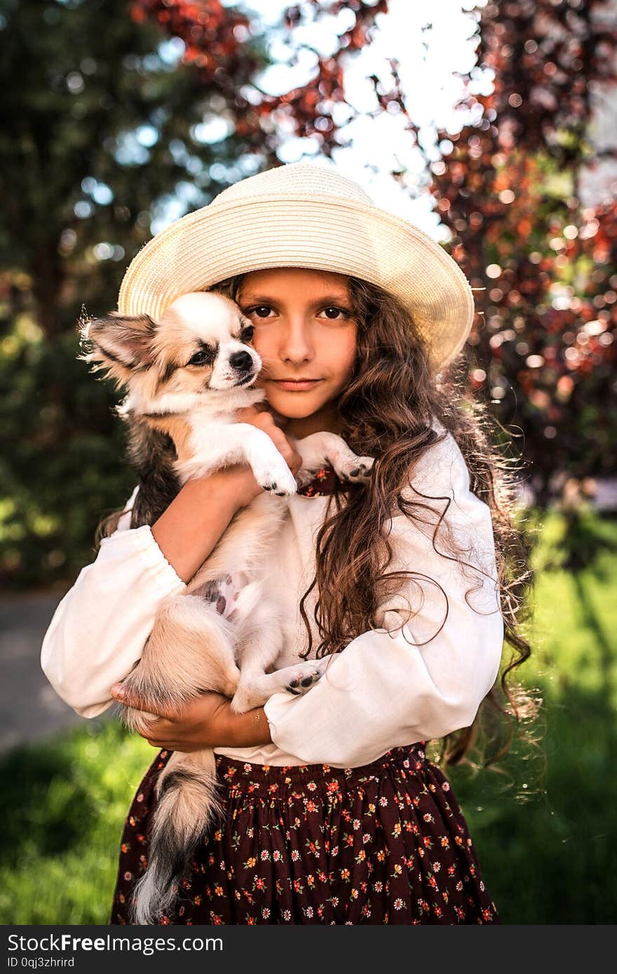 Little nice girl hugging a dog outdoors.