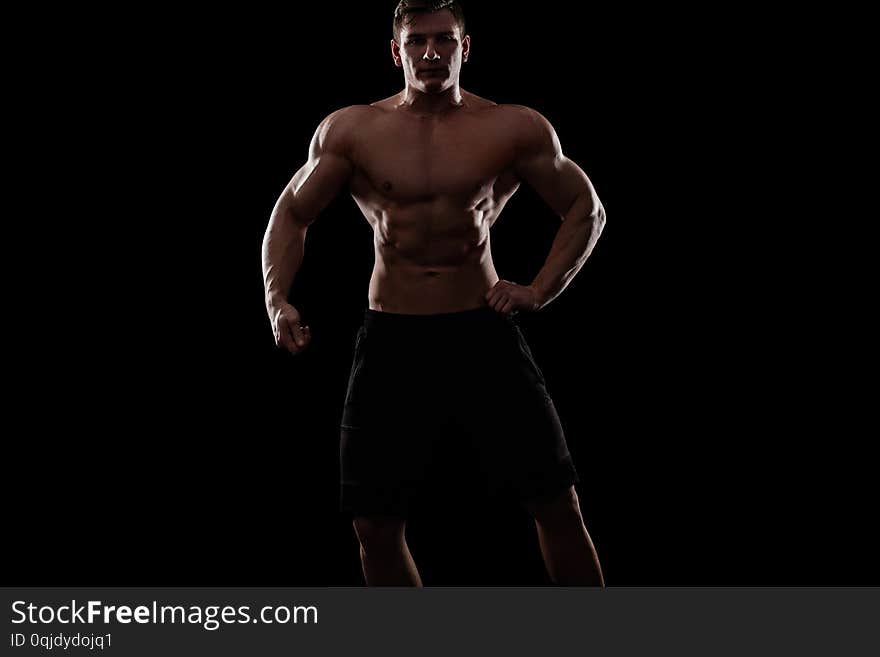 Bodybuilding competitions on the scene. Man sportsmen physique and athlete. Black background with lights.