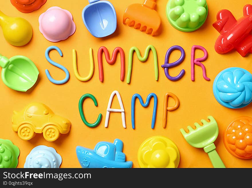 Text SUMMER CAMP made of modelling clay and different sand molds on color background, flat lay