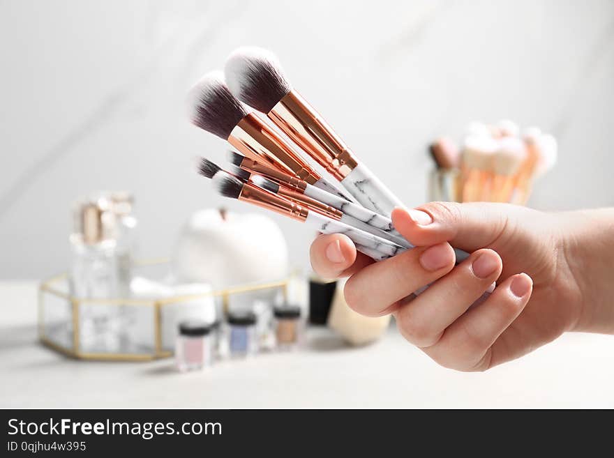 Woman holding set of makeup brushes on blurred background, closeup. Woman holding set of makeup brushes on blurred background, closeup