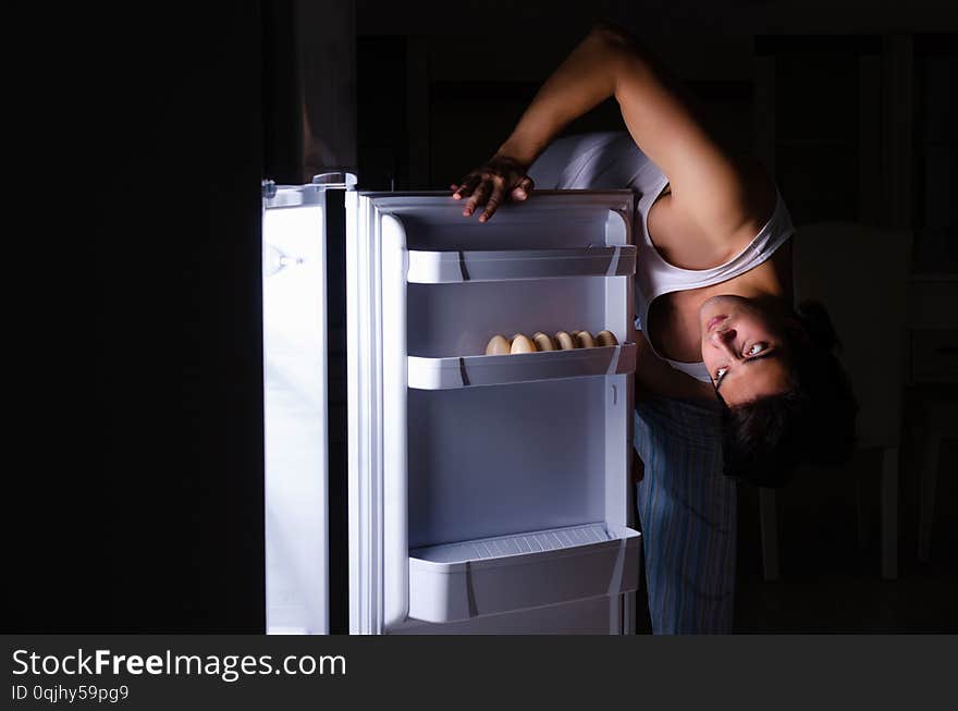The man breaking diet at night near fridge