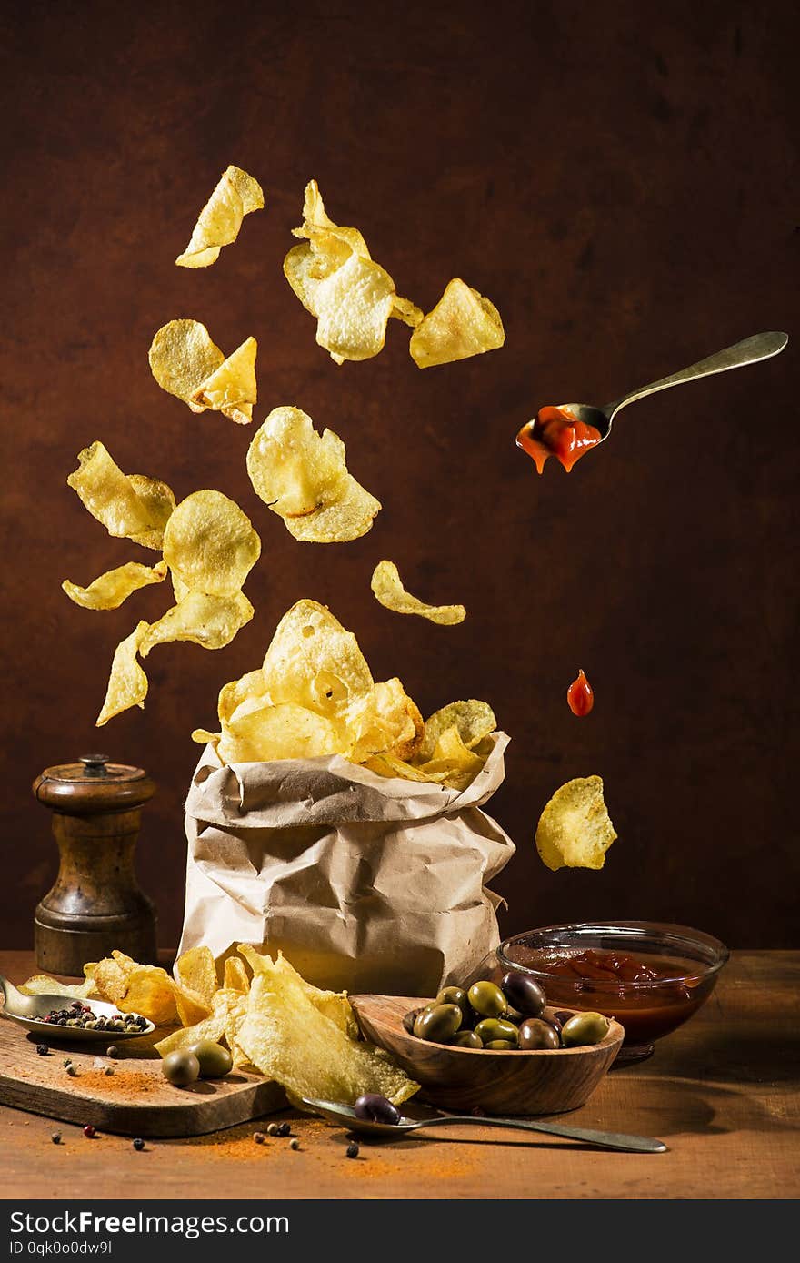 Paper bag with fries and spices on a rustic wooden board. Paper bag with fries and spices on a rustic wooden board