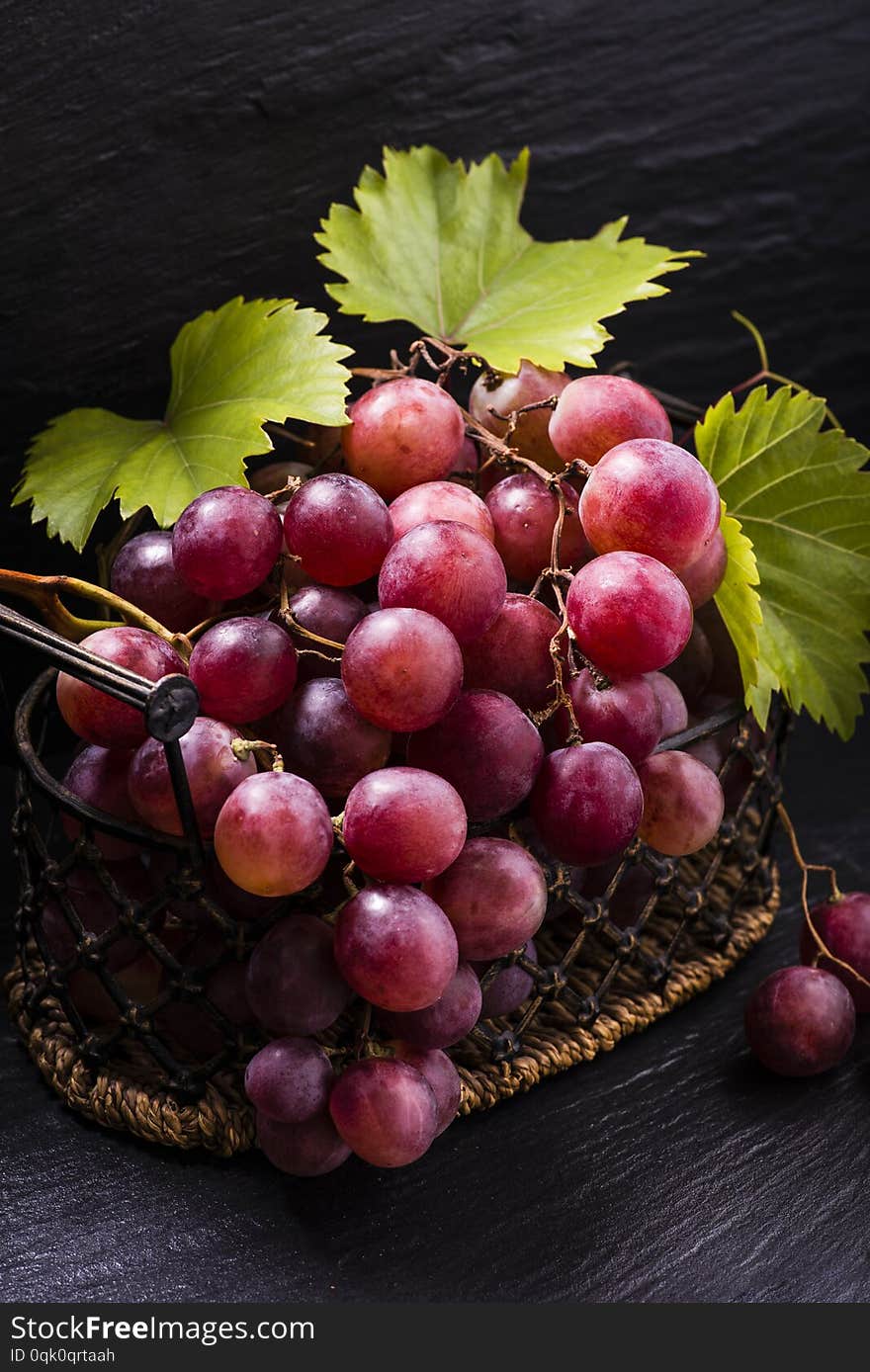 In the vintage basket red table grapes with leaves .still life. In the vintage basket red table grapes with leaves .still life