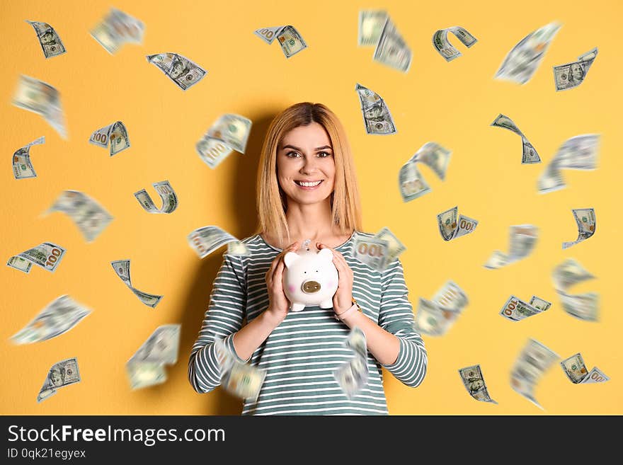 Happy woman with piggy bank and flying money on color background