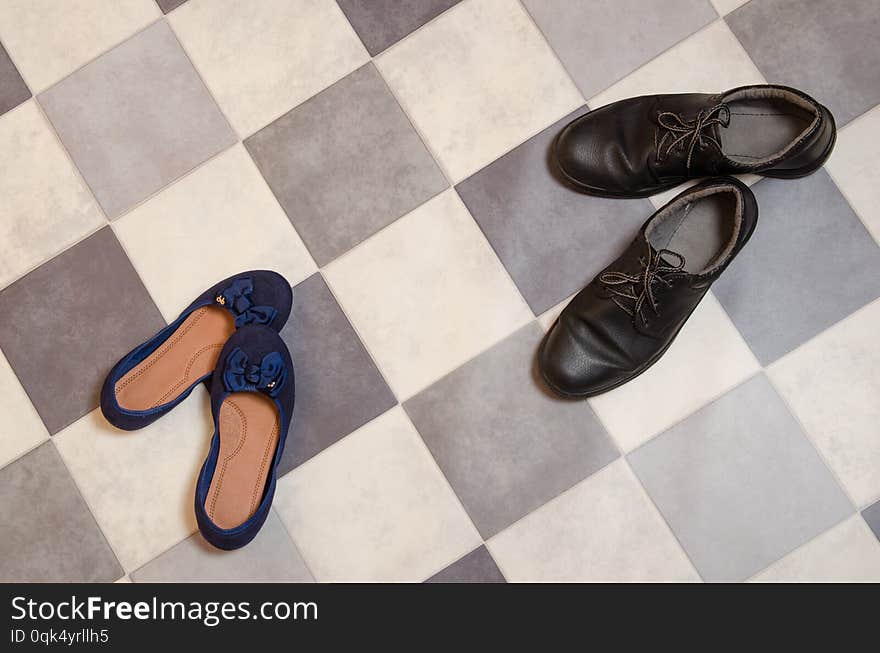 Light and comfortable blue women`s shoes and man`s shoes on  black and white checkered floor.