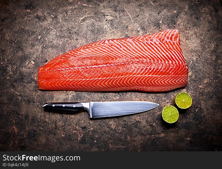 Fresh salmon steak red fish on grunge background with knife and cuted lime top view.