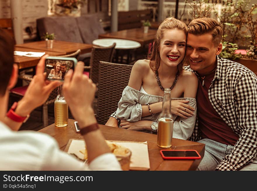 Happy Couple Being Photographed By Their Friend At The Bar.