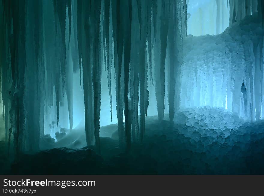 Huge ice icicles. Fragment of large blocks of ice frozen waterfall of water. Blue ice cavern background. Frozen stream waterfall. Huge ice icicles. Fragment of large blocks of ice frozen waterfall of water. Blue ice cavern background. Frozen stream waterfall