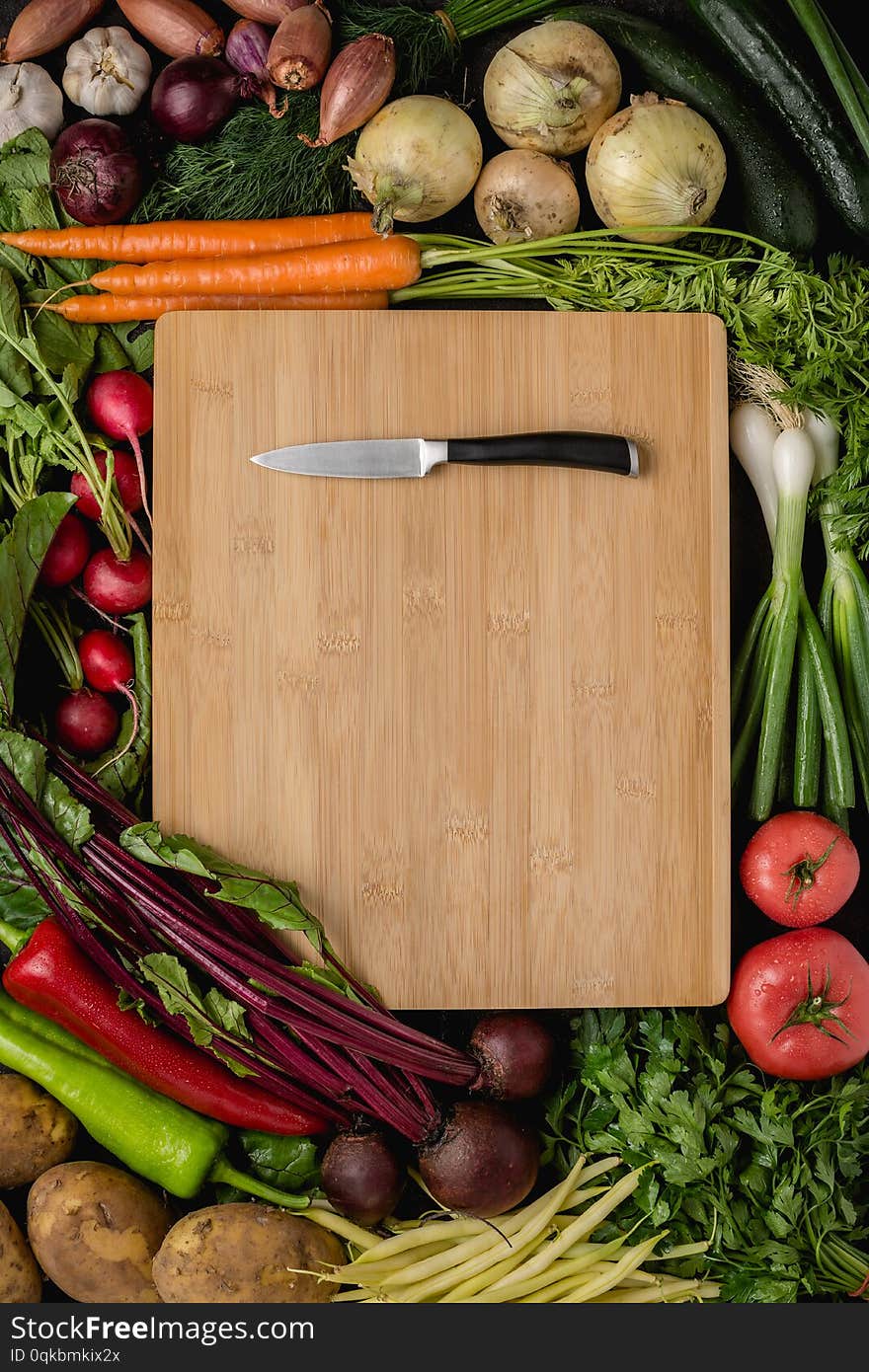 Small Kitchen Knife on Wood Cutting Board with Fresh Vegetables. Vegan Raw Food. Healthy Eating Concept.