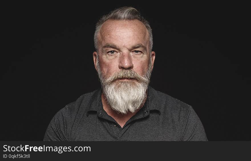 Portrait of a senior man isolated on black background. Close up of man with a white beard looking at camera. Portrait of a senior man isolated on black background. Close up of man with a white beard looking at camera