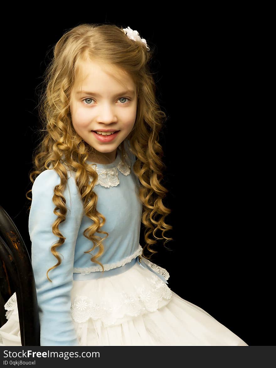 Portrait of a beautiful little girl sitting on an old Viennese chair, studio on a black background. Concept and fashion, photo on the cover of the magazine. Portrait of a beautiful little girl sitting on an old Viennese chair, studio on a black background. Concept and fashion, photo on the cover of the magazine.