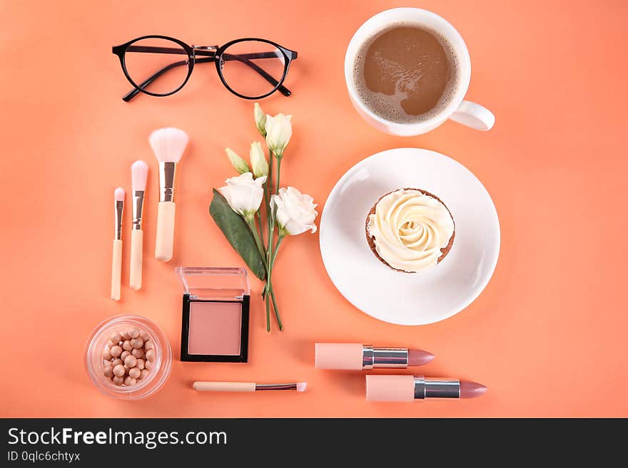 Flat lay composition with cosmetic products, cup of coffee and cupcake on color background