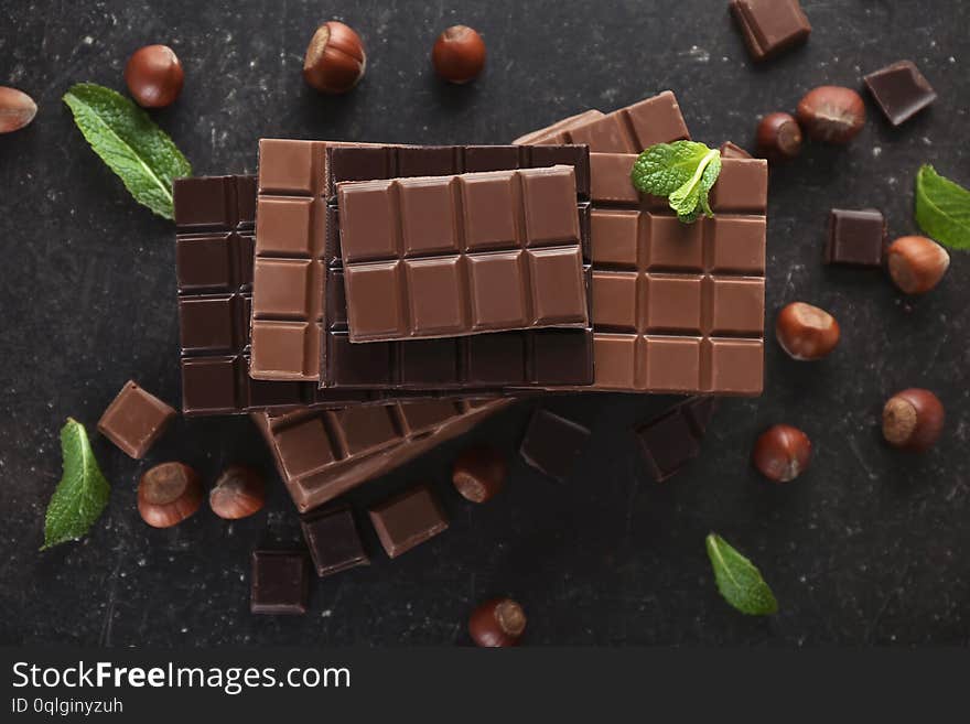 Flat Lay Composition With Tasty Chocolate, Mint And Hazelnuts On Dark Background