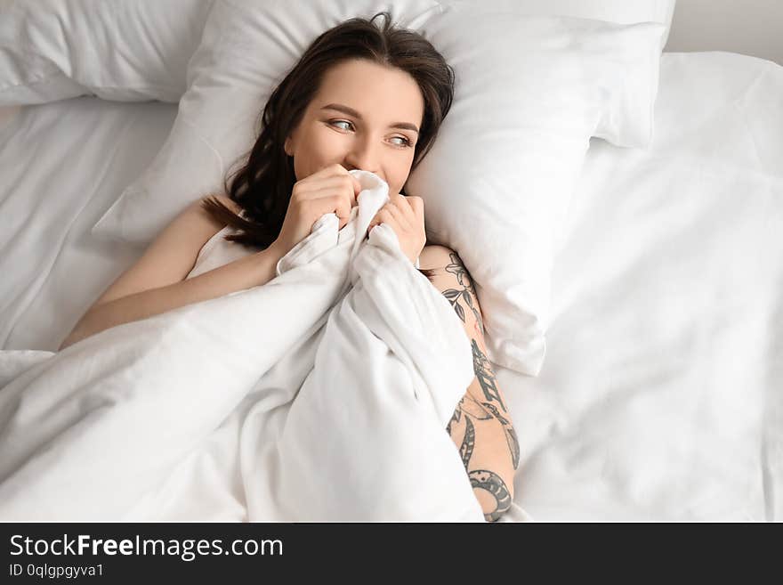 Young beautiful woman lying on bed in morning